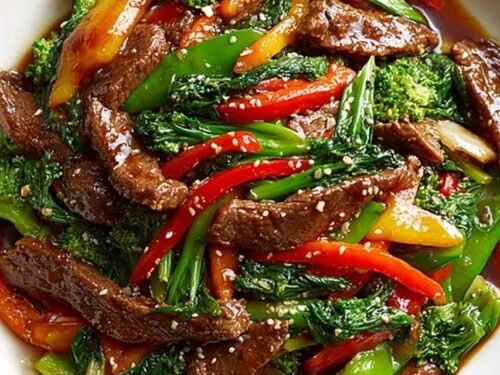 Beef stir fry with vegetables over steamed jasmine rice with green onions and sesame seeds