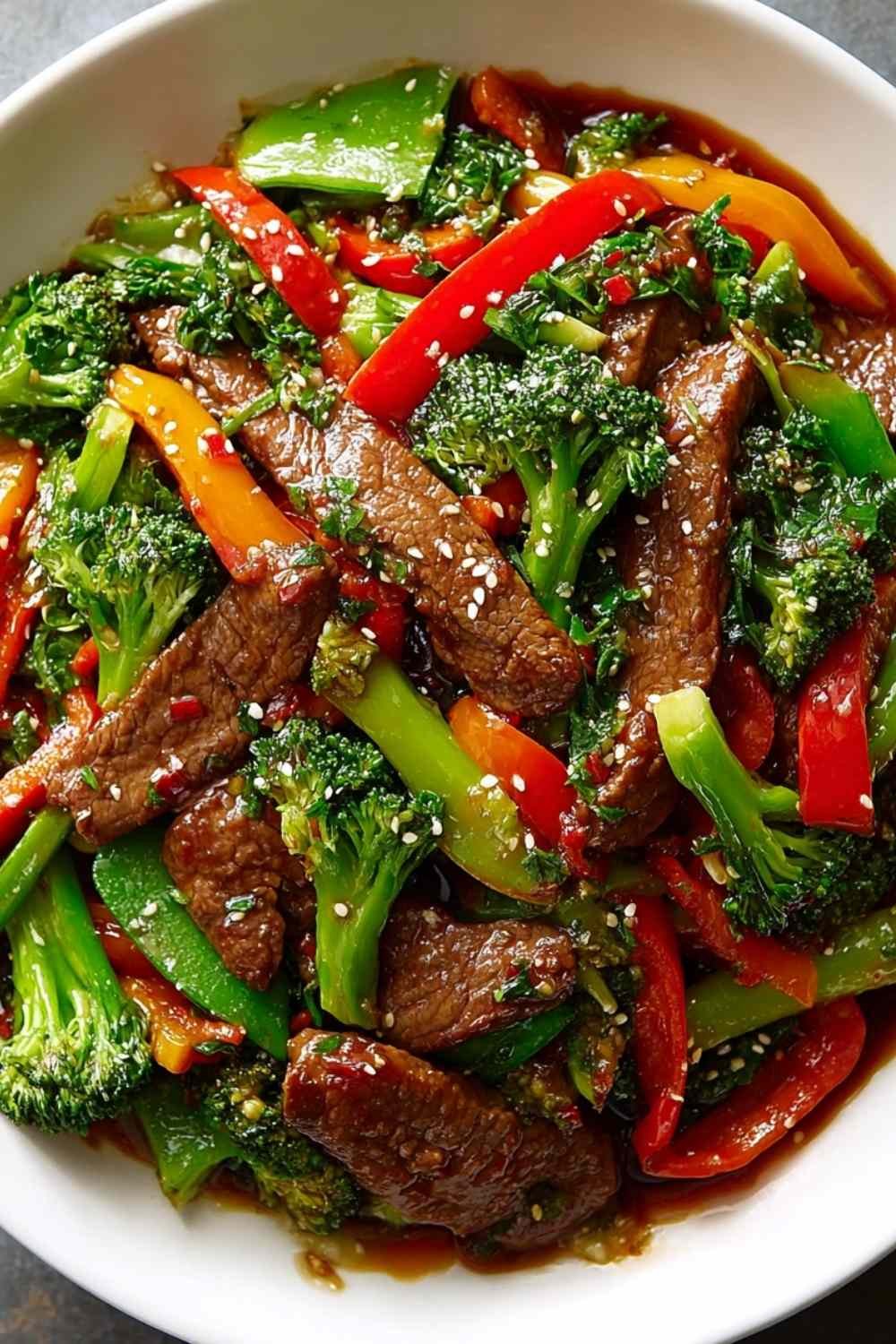 Beef stir fry with vegetables over steamed jasmine rice with green onions and sesame seeds