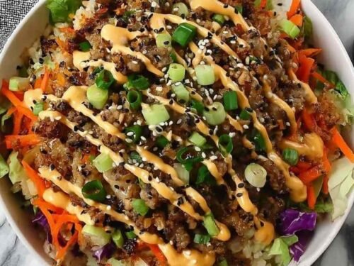 Blackstone Egg Roll in a Bowl with ground pork, shredded cabbage, carrots, sesame seeds, and spicy mayo served in a white bowl