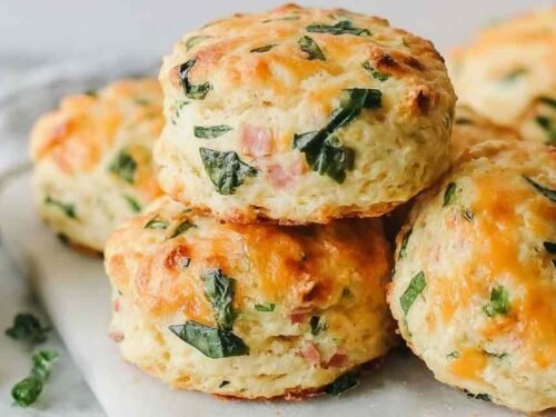 Breakfast protein biscuits with melted cheddar cheese cooling on a parchment lined baking sheet fresh from the oven