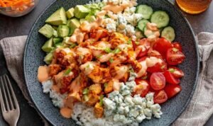 High protein buffalo chicken bowls with rice, fresh vegetables, and creamy buffalo Greek yogurt dressing