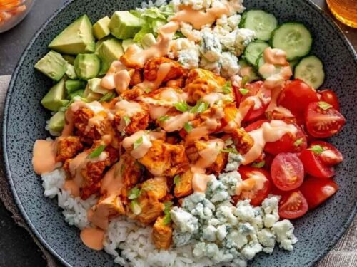 High protein buffalo chicken bowls with rice, fresh vegetables, and creamy buffalo Greek yogurt dressing