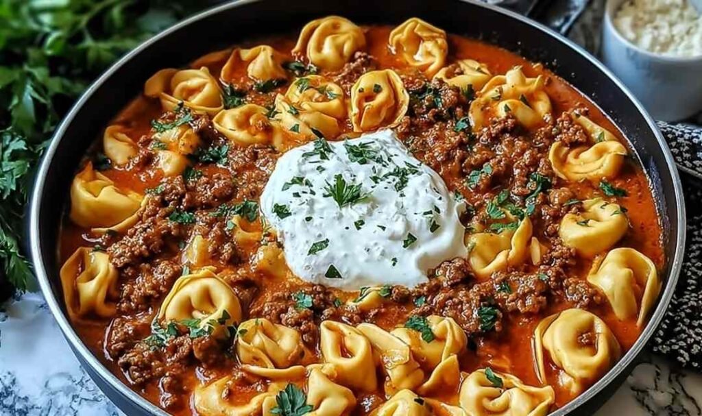 Cheesy Beef Enchilada Tortellini in a skillet topped with melted cheese and fresh cilantro