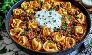 Cheesy Beef Enchilada Tortellini in a skillet topped with melted cheese and fresh cilantro