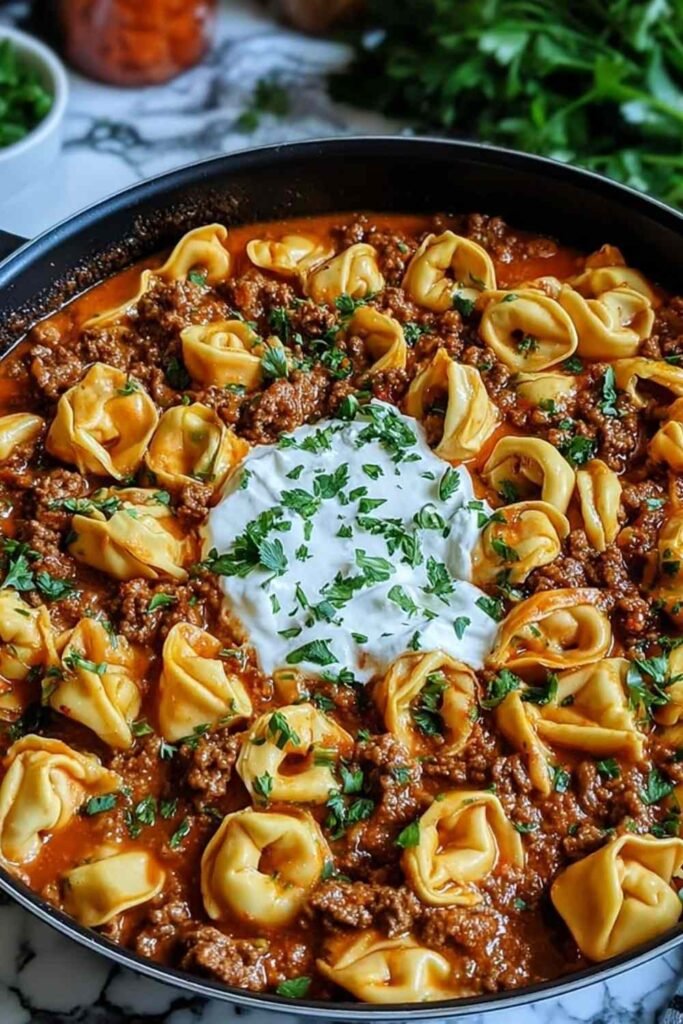 Cheesy Beef Enchilada Tortellini in a skillet topped with melted cheese and fresh cilantro