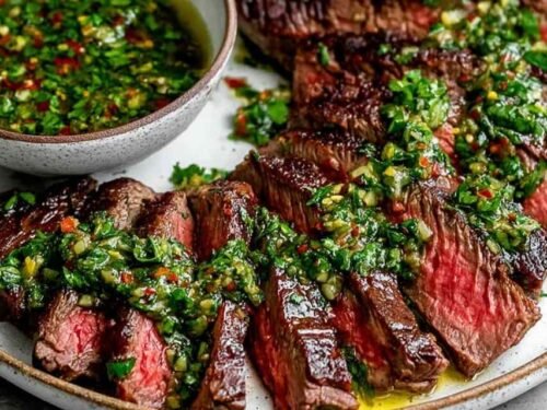 Chimichurri Steak sliced against the grain on a wooden cutting board with vibrant green chimichurri herb sauce drizzled over golden seared ribeye slices