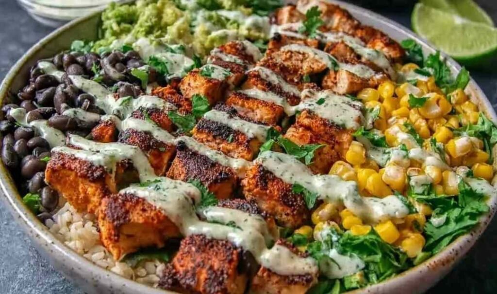 Chipotle chicken bowl with sliced grilled chicken, black beans, charred corn, avocado, and creamy chipotle sauce in a white bowl