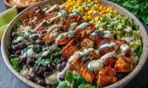 Chipotle chicken bowl with sliced grilled chicken, black beans, charred corn, avocado, and creamy chipotle sauce in a white bowl
