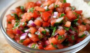 Bowl of copycat Chipotle pico de gallo with diced tomatoes, white onion, cilantro, and jalapeño with lime wedge on the side