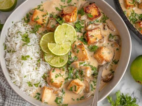 Crispy coconut lime tofu served over jasmine rice in a white bowl, garnished with fresh cilantro and lime wedges