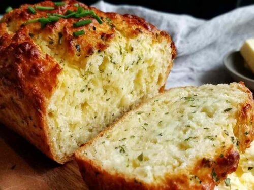 Golden sliced cottage cheese bread loaf on a wooden cutting board showing a moist high-protein crumb