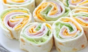 Turkey roll ups with cheddar and cream cheese sliced into rounds on a wooden cutting board