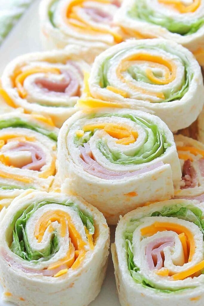 Turkey roll ups with cheddar and cream cheese sliced into rounds on a wooden cutting board