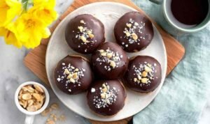 High Protein Frozen Peanut Butter Greek Yogurt Bites High Protein Frozen Peanut Butter Greek Yogurt Bites coated in dark chocolate with flaky sea salt on parchment paper