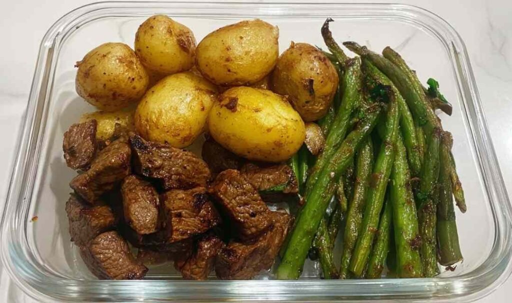 Garlic Balsamic Steak Bites in a meal prep bowl with roasted baby gold potatoes and blistered green beans