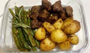 Garlic Balsamic Steak Bites in a meal prep bowl with roasted baby gold potatoes and blistered green beans