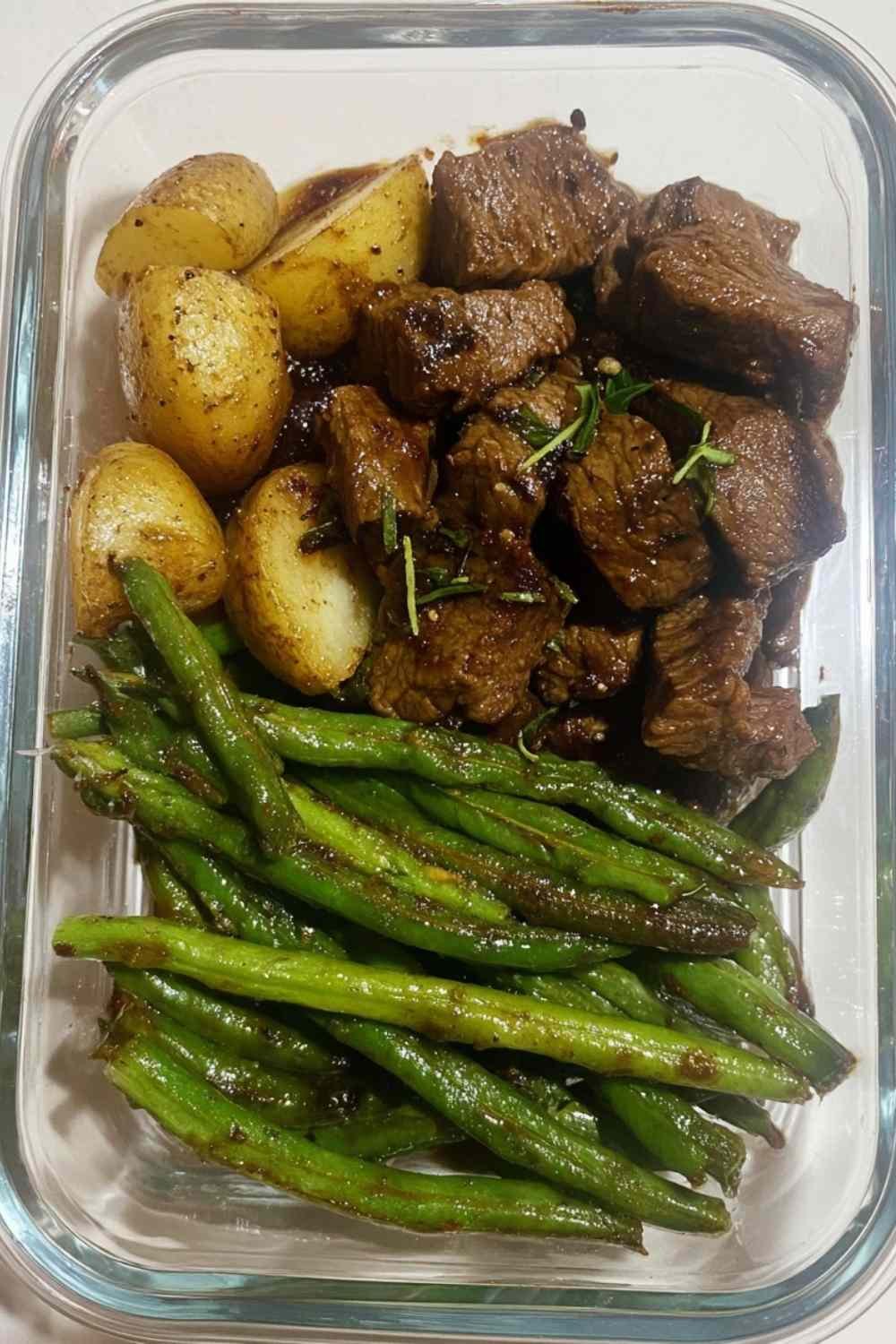 Garlic Balsamic Steak Bites in a meal prep bowl with roasted baby gold potatoes and blistered green beans