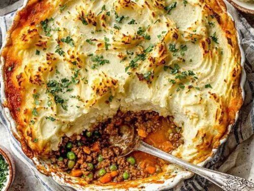 Ground turkey cottage pie in a cast iron skillet with mashed potato topping and Parmesan before baking
