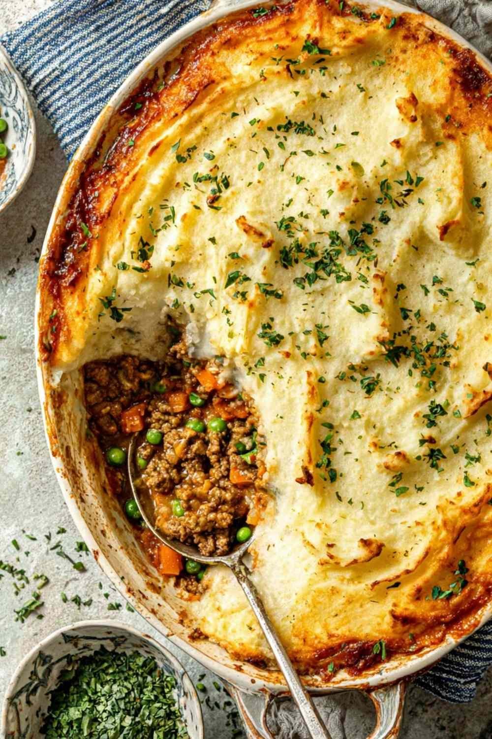 Ground turkey cottage pie in a cast iron skillet with mashed potato topping and Parmesan before baking
