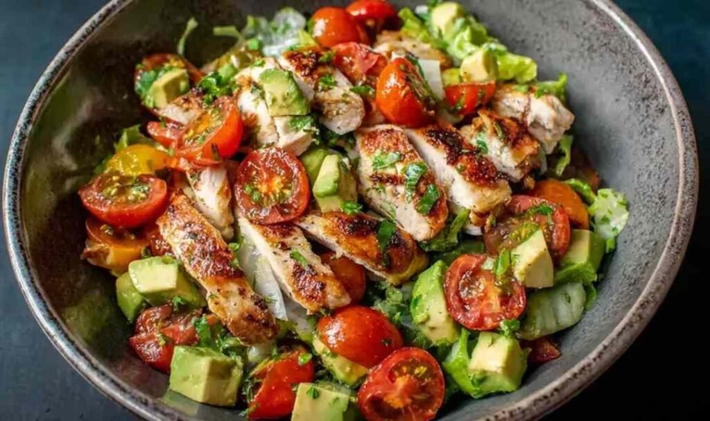 Healthy avocado chicken salad with diced chicken, tomatoes, red onion, and lime in a white bowl