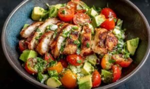 Healthy avocado chicken salad with diced chicken, tomatoes, red onion, and lime in a white bowl