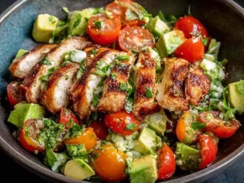 Healthy avocado chicken salad with diced chicken, tomatoes, red onion, and lime in a white bowl