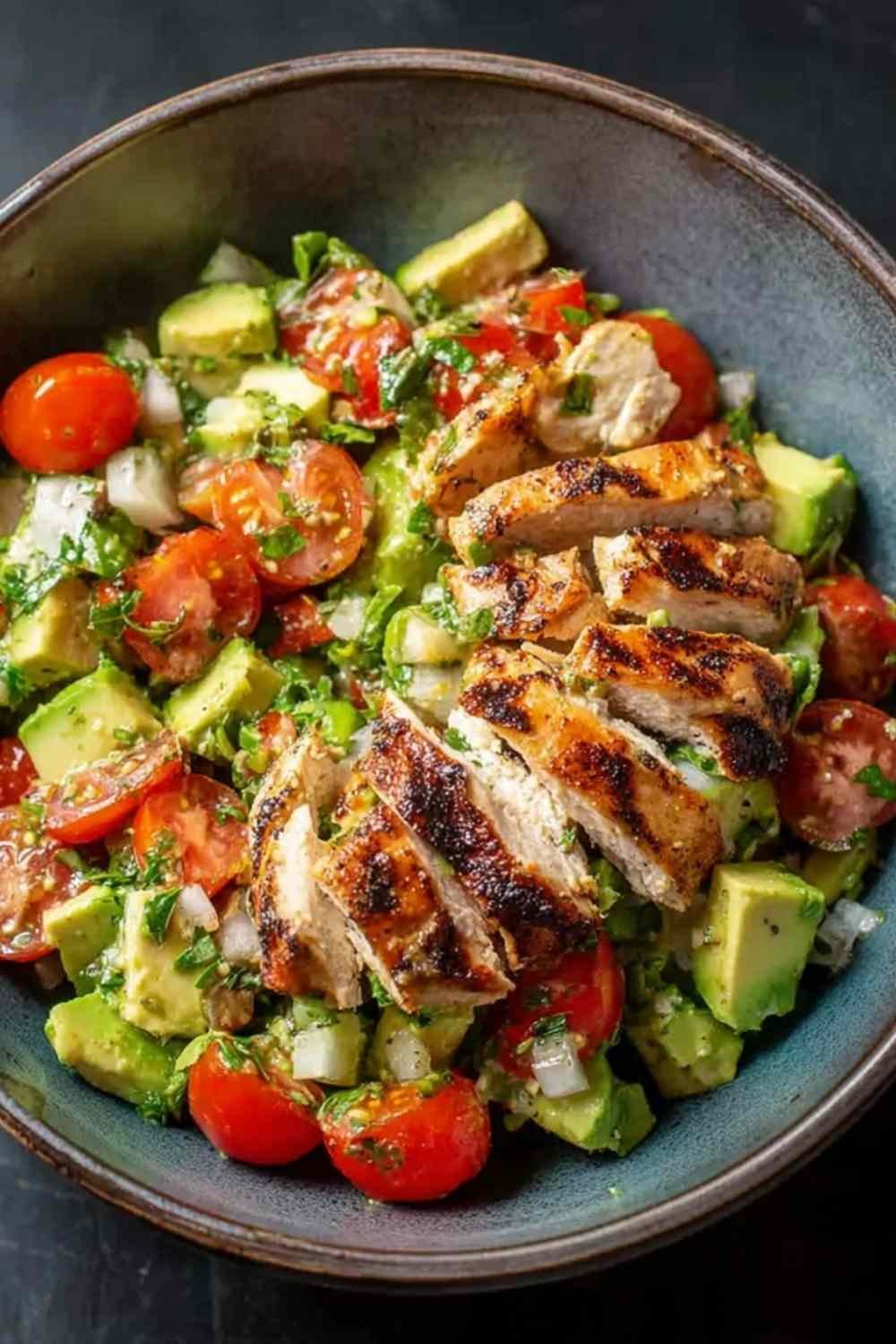 Healthy avocado chicken salad with diced chicken, tomatoes, red onion, and lime in a white bowl