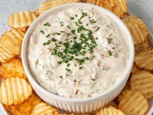 Healthy onion dip made with caramelized onions and Greek yogurt served in a white bowl with kettle chips and fresh vegetables