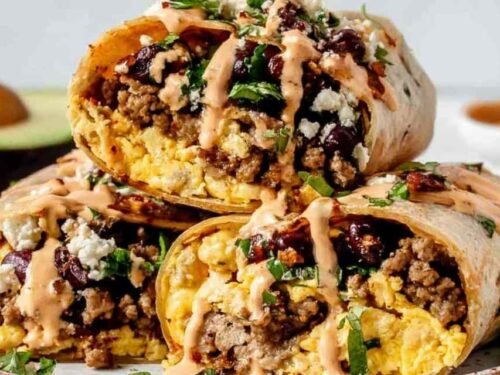 High protein breakfast burrito wrapped in aluminum foil on a baking sheet ready for the freezer