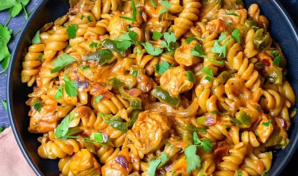 High protein chicken fajita pasta in a large skillet with creamy cheddar sauce, golden chicken pieces, and diced bell peppers