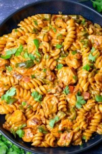 High Protein Chicken Fajita Pasta High protein chicken fajita pasta in a large skillet with creamy cheddar sauce, golden chicken pieces, and diced bell peppers