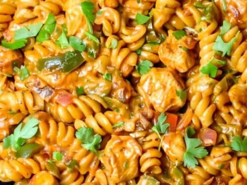 High protein chicken fajita pasta in a large skillet with creamy cheddar sauce, golden chicken pieces, and diced bell peppers