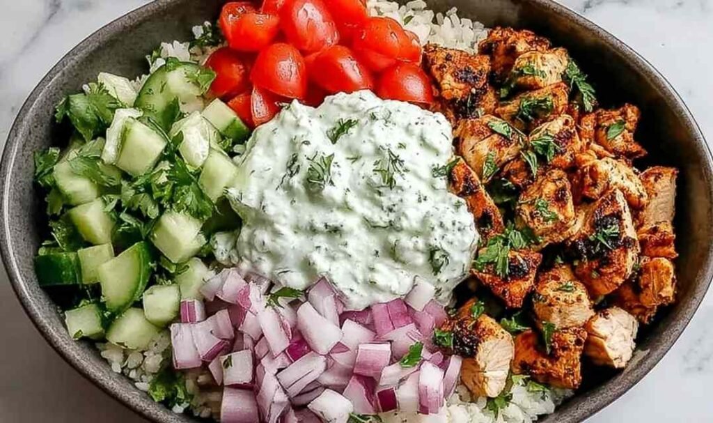 Chicken gyro bowl with marinated chicken tzatziki diced tomato cucumber red onion and feta over white rice