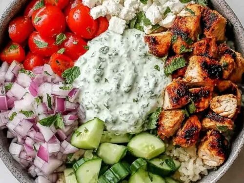 Chicken gyro bowl with marinated chicken tzatziki diced tomato cucumber red onion and feta over white rice