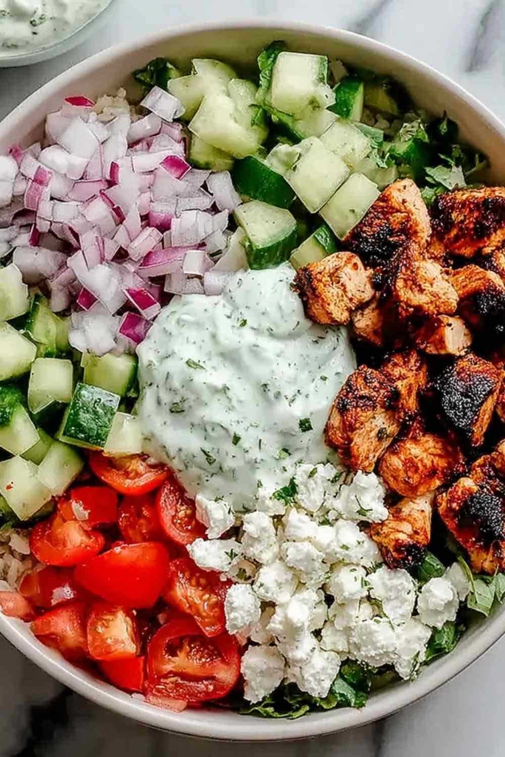 Chicken gyro bowl with marinated chicken tzatziki diced tomato cucumber red onion and feta over white rice