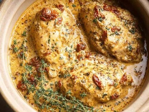 High protein crockpot marry me chicken in a slow cooker with creamy sun-dried tomato sauce and fresh basil garnish