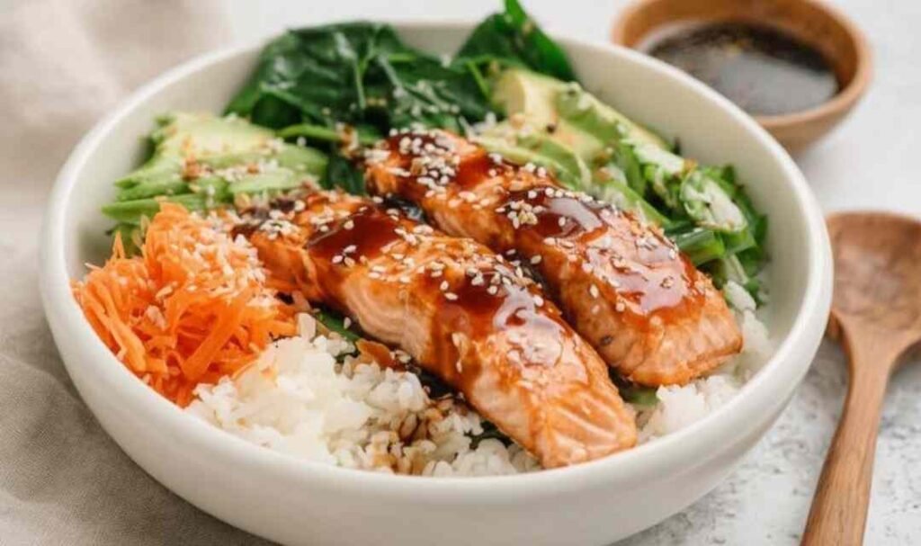 High protein low calorie teriyaki salmon bowl with glazed salmon broccoli edamame cucumber carrots and sesame seeds over rice