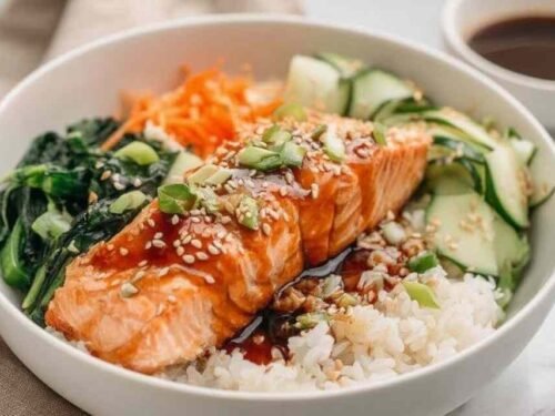 High protein low calorie teriyaki salmon bowl with glazed salmon broccoli edamame cucumber carrots and sesame seeds over rice