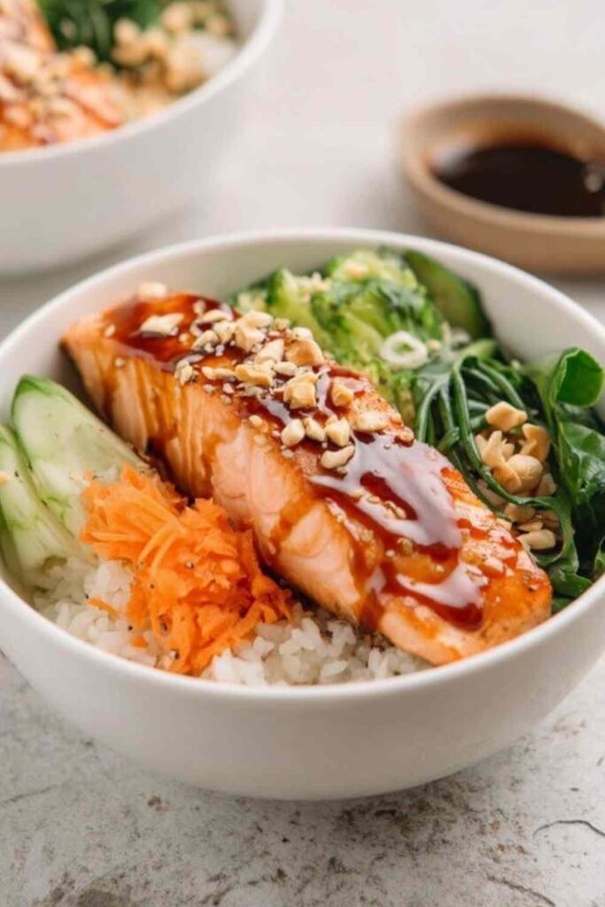 High protein low calorie teriyaki salmon bowl with glazed salmon broccoli edamame cucumber carrots and sesame seeds over rice