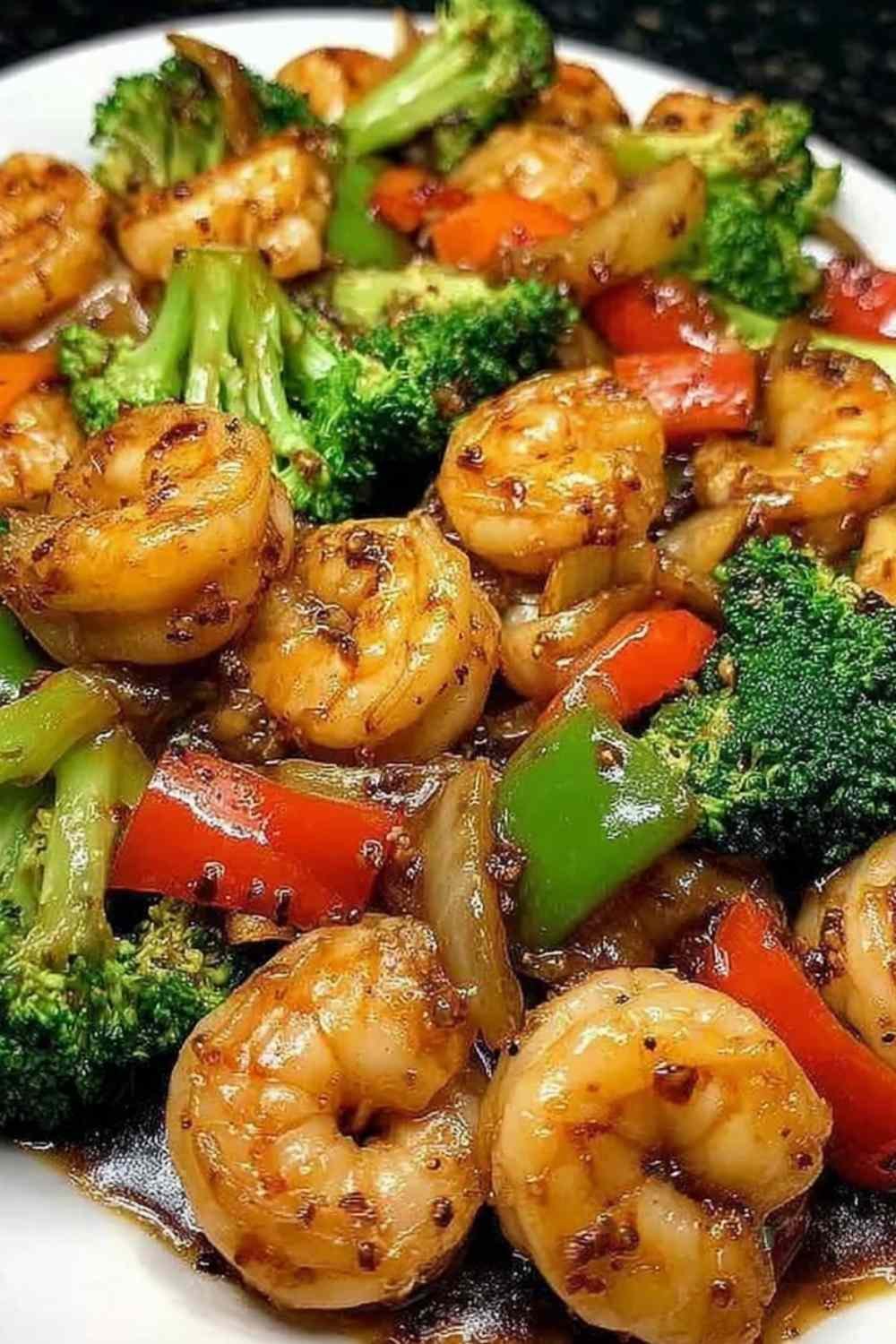 High-protein shrimp stir fry with noodles, broccoli, snap peas, and bell pepper in a glossy garlic-soy sauce served in a wok