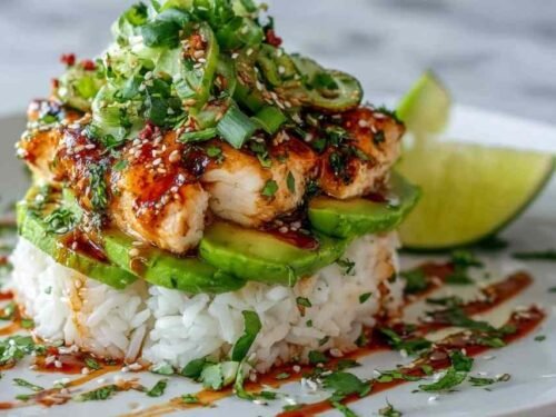 Honey lime chicken avocado rice stack in a bowl with sliced grilled chicken, avocado, black beans, corn, and fresh cilantro
