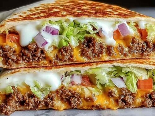 Keto crunchwraps recipe cut in half showing layers of seasoned beef, cheese sauce, and crispy low-carb tortilla