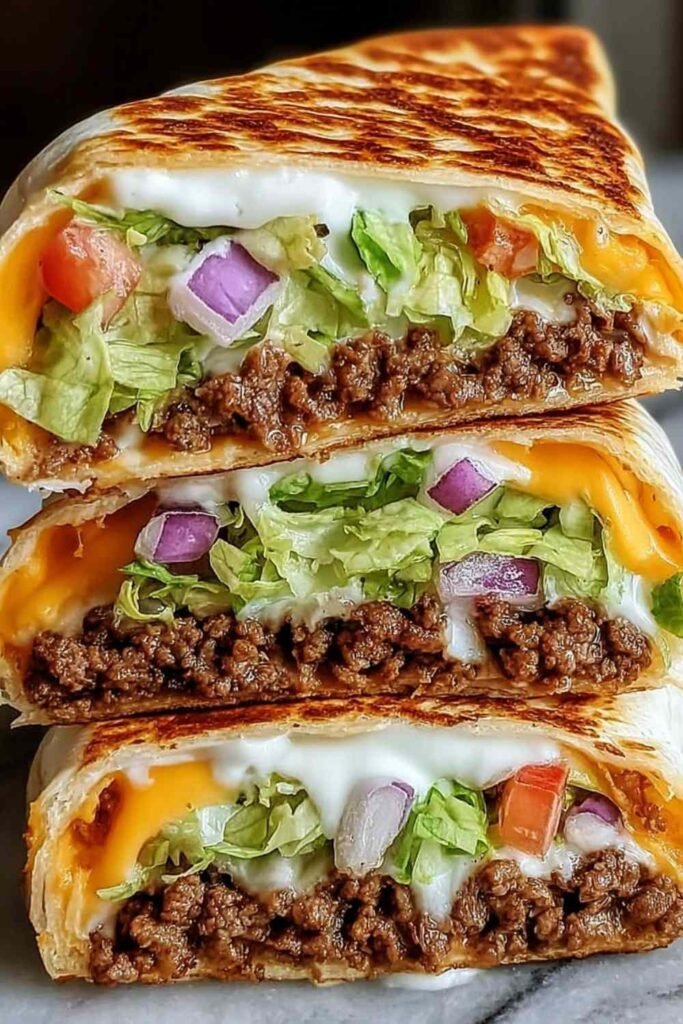 Keto crunchwraps recipe cut in half showing layers of seasoned beef, cheese sauce, and crispy low-carb tortilla