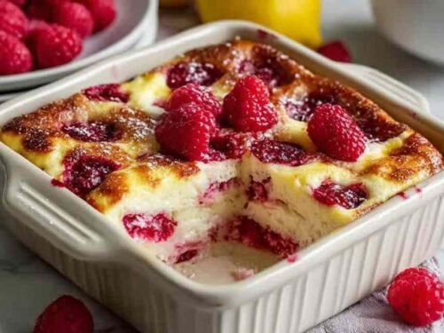 Lemon raspberry cottage cheese bake in a white baking dish cut into nine squares with golden edges and visible raspberries
