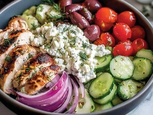 Low-carb Greek chicken bowls with sliced marinated chicken, homemade tzatziki, crumbled feta, cherry tomatoes, and Kalamata olives