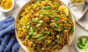 Mujadara lentils and rice on a serving platter topped with caramelized onions, fresh parsley, and lemon wedges