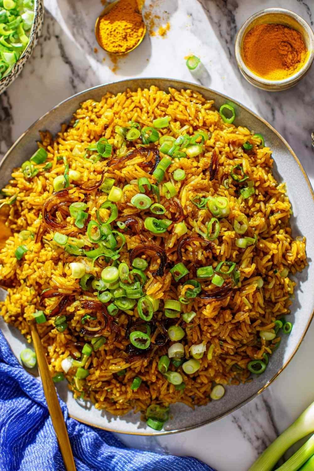 Mujadara lentils and rice on a serving platter topped with caramelized onions, fresh parsley, and lemon wedges