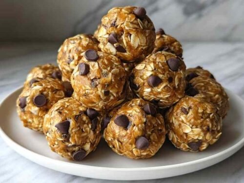 No-bake peanut butter energy bites with oats and mini chocolate chips arranged in a small white bowl on a kitchen counter