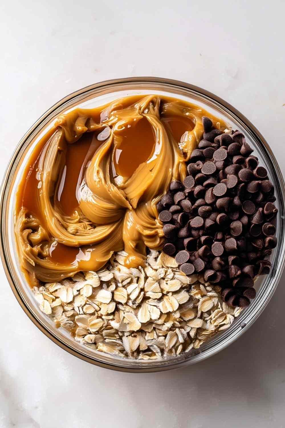 No-bake peanut butter energy bites with oats and mini chocolate chips arranged in a small white bowl on a kitchen counter