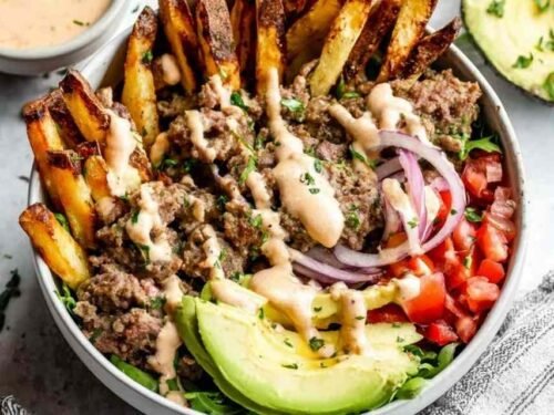 Paleo Burger Bowls with Fries topped with ground beef, crispy bacon, avocado, cherry tomatoes, pickles, and special sauce served in a white bowl